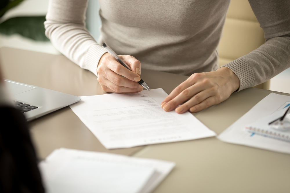 Woman,Signing,Document,,Focus,On,Female,Hand,Holding,Pen,,Putting