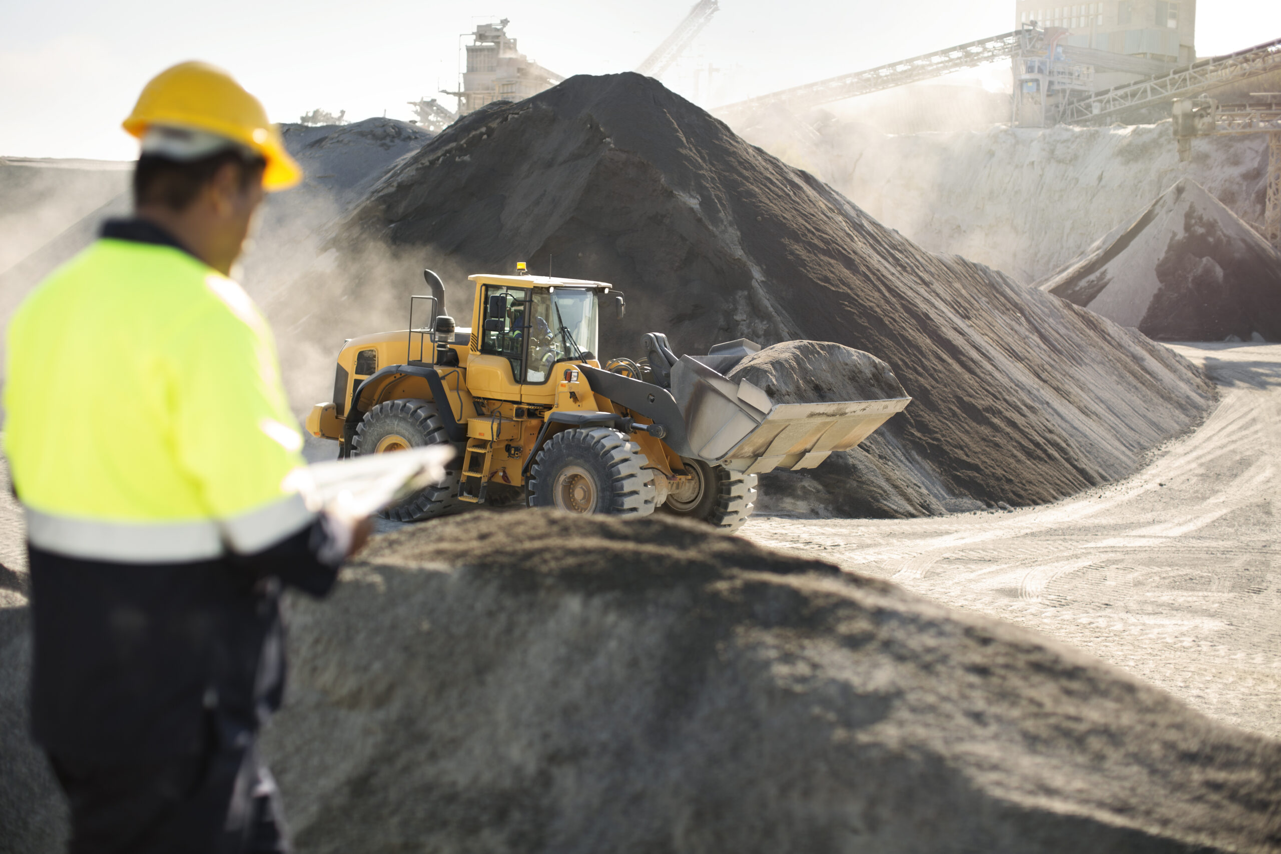 Worker standing at quarry, using clipboard