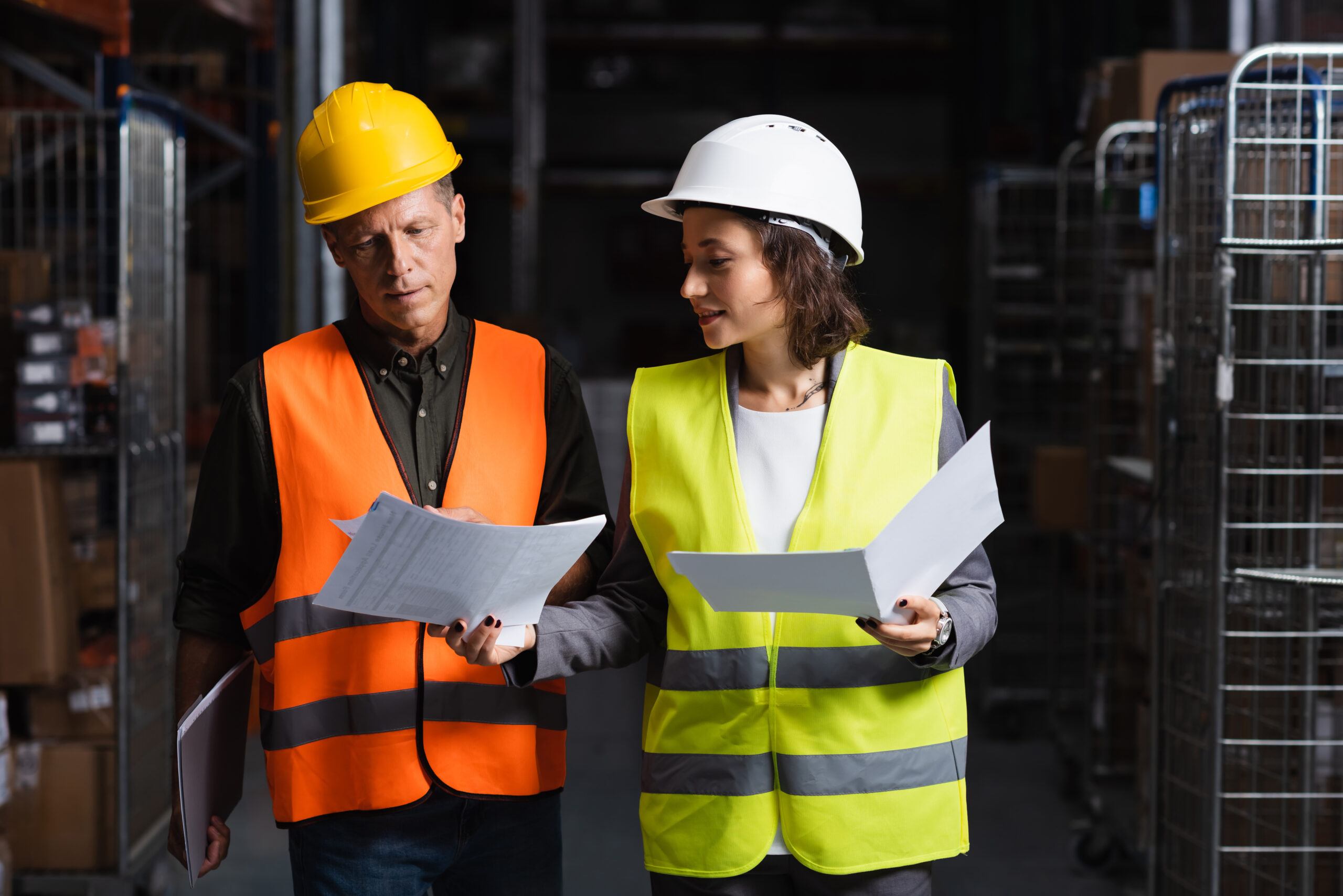 What are the Requirements for Safety Data Sheets? Image of colleagues-in-safety-vests-walking-in-warehouse-looking-at-documents