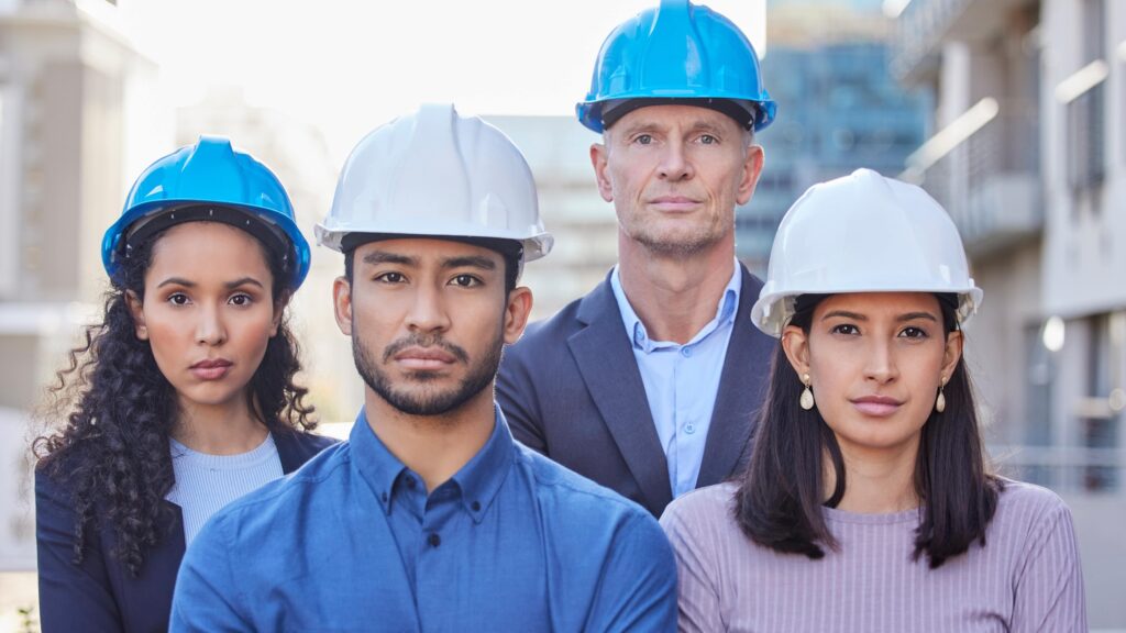 Two female and two male workers wearing hard hats with their arms folded across their chests