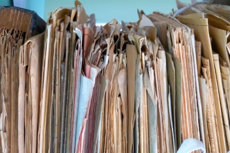 Messy stack of file folders showing poor records management practices