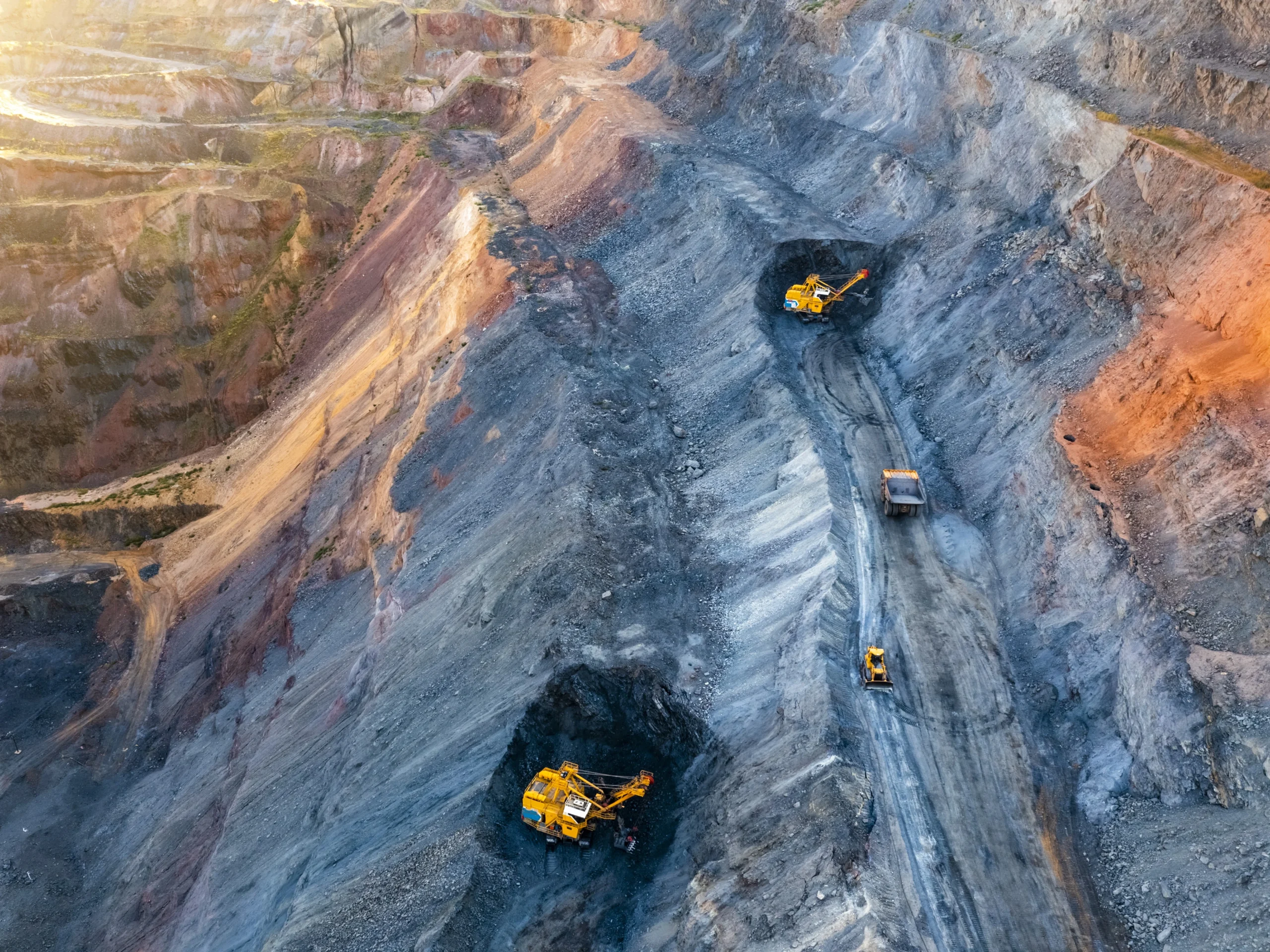 An aerial view of a mining excavation site with two large pieces of equipment.