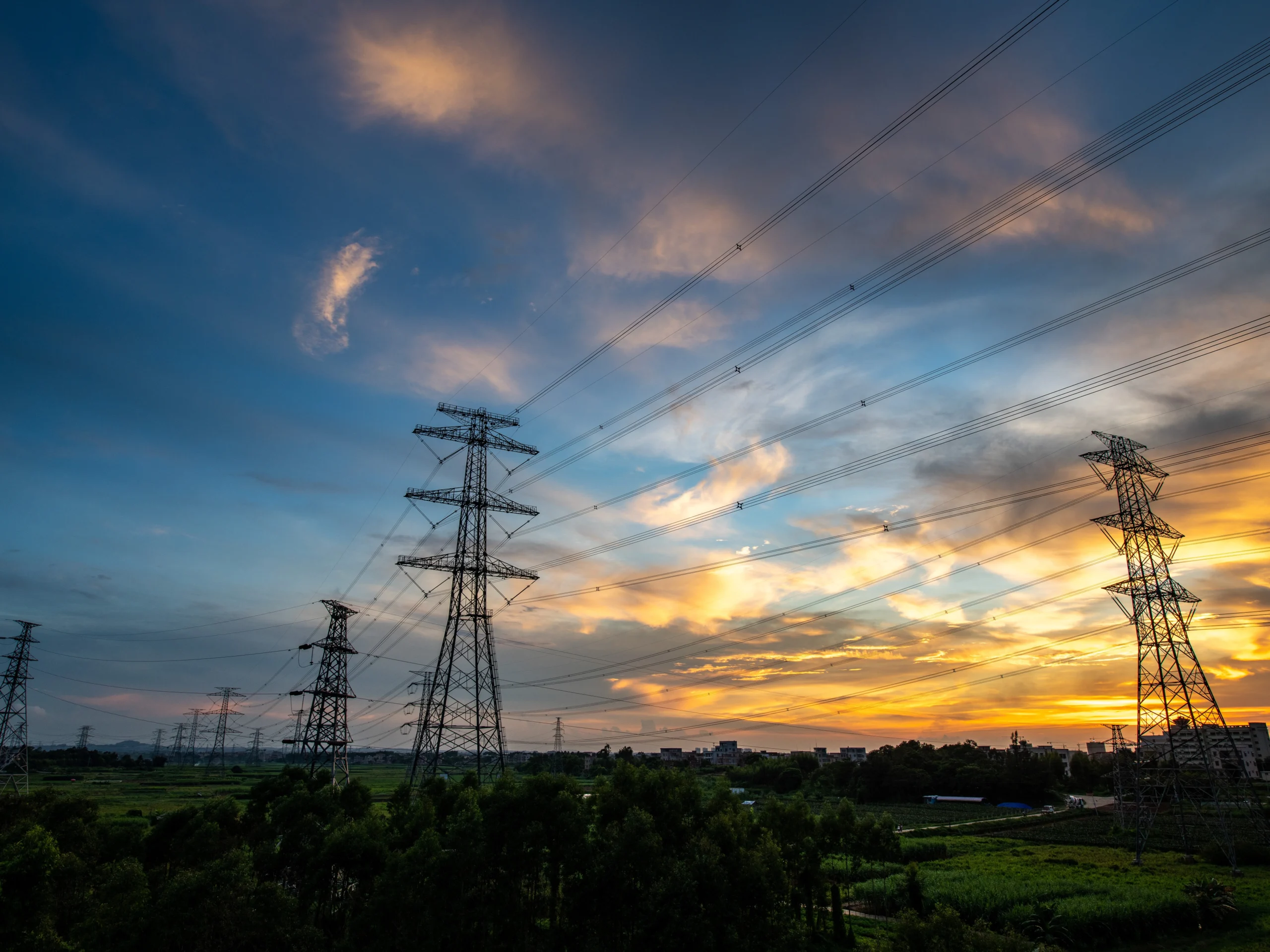 Scenic view of power lines with a sunset and deep blue sky.