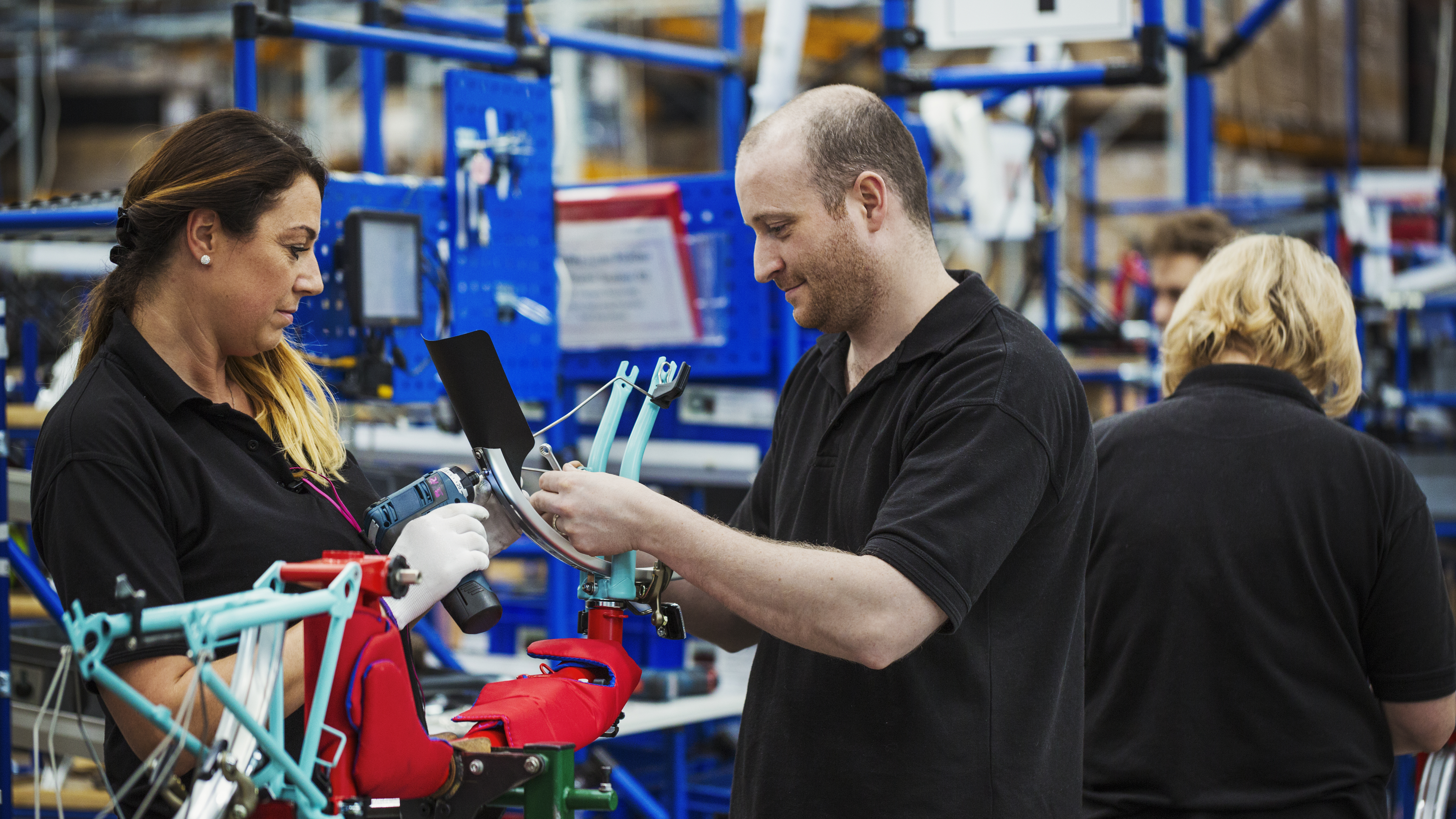 Factory workers collaborating on assembling a bicycle frame, demonstrating how simplifying safety processes creates clearer, more efficient workflows in industrial environments.