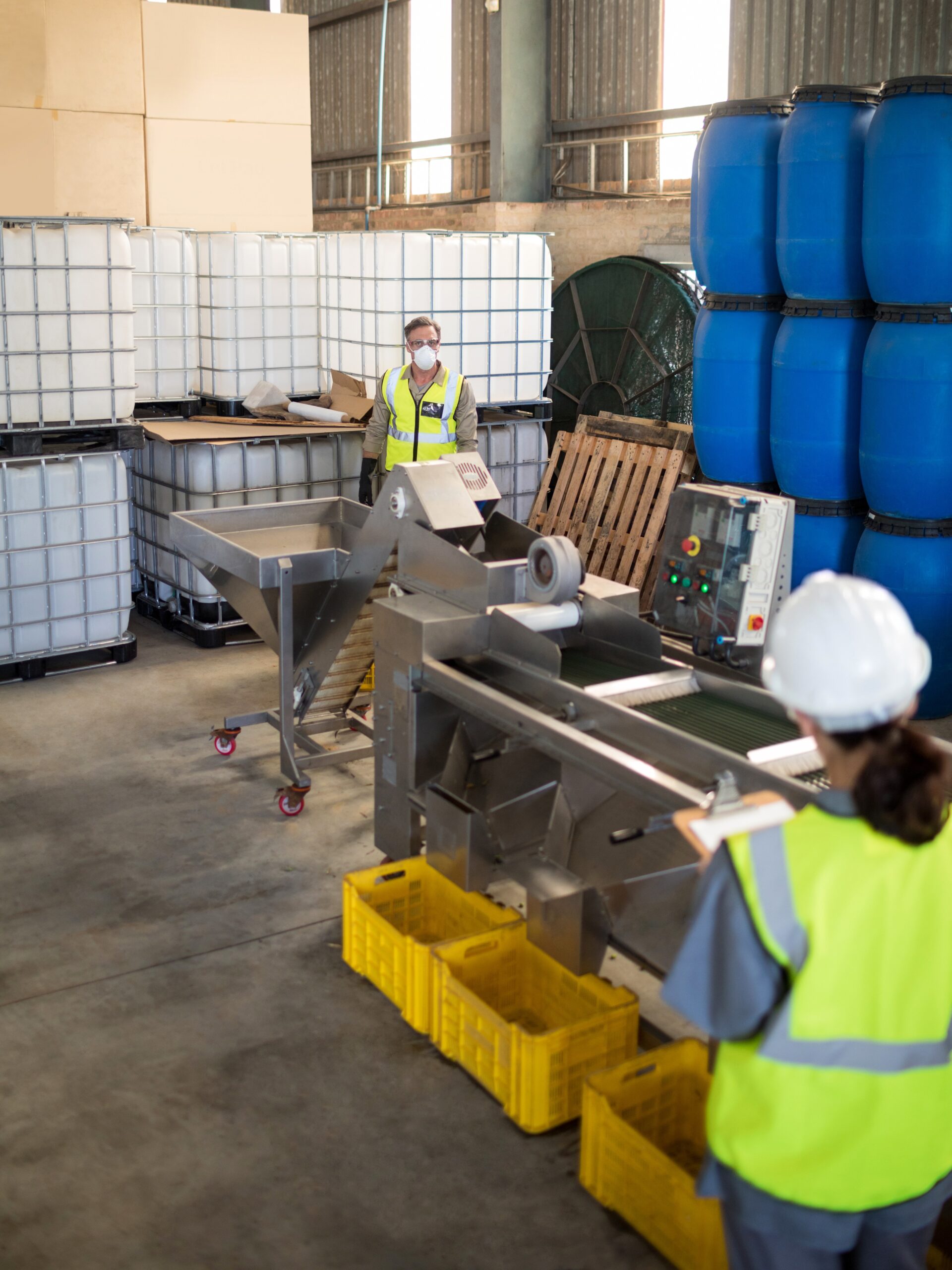 Two workers stand apart in a waste processing facility