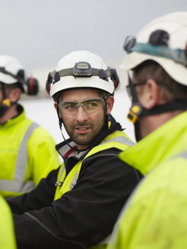 Several wind turbine workers in white hard hats and head lamps.